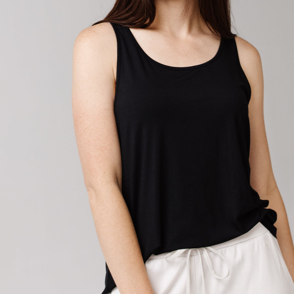 Woman in a black Cozy Earth Stretch Knit Tank and white shorts is shown from the neck down with a neutral background |Color:Black